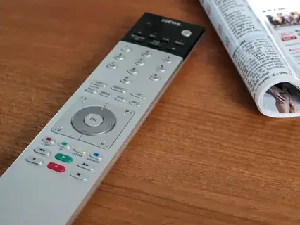 Controle remoto sobre a mesa ao lado de um jornal