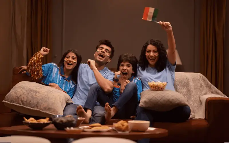 Família e amigos reunidos diante da TV na sala