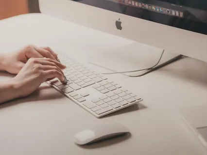 Mãos com computador e teclado no escritório